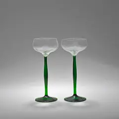 Peter Behrens, Pair of wine glasses, designed 1898, Clear glass bowls, on green shaped stems and a circular spreading foot