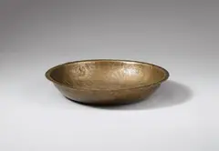 Probably German 12th century, A probably German 12th century bronze dish with engraved depictions of knights., With remains of gilding.. The dish is made of "tombak" bronze, which is copper mixed with a larger portion of tin, and belongs to a group of 11 similar dishes kept in various European collections, all of which have been published by Josepha Weitzmann-Fiedler (ibid.) in her seminal work on the subject. The centre is engraved with a six-pointed star surrounded by depictions of four knights dressed in chainmail, carrying shields and upraised swords, as well as four stylised palmtrees. With minor wear and rubbing