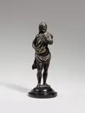 Probably Italy 17th century, A probably Italian figure of John the Baptist (?), 17th century, Bronze, cast in the round, chased, with an older patina. A full-length depiction of a youthful, bearded man dressed solely in a cloth draped around his body and standing upon a three-sided plinth. The facial features and style of the hair could suggest a depiction of Saint John the Baptist. Some fingers of the left hand lost, a drilled hole to the body beside the right hand. Partially rubbed. Mounted to a wooden socle