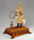 Léopold Lambert, A musical automaton formed as a clown taming a bear, Wind-up mechanism, firmly mounted original key and locking button. Painted wooden and papier mache head with glass eyes, metal tongue, porcelain hands, embroidered textile, fur and stuffing. The clown's arms and the bear's head move to the music. The key monogrammed LB. Labelled "LB La Rosière Modèle déposé" to the front of the socle. Label of the merchant "Au nain bleu E. Chauvière, Boul. des Capucines 27 Paris" to the underside. Soiled, the bear fur damaged, localised damage to the facial polychromy, wear to the velvet. H
