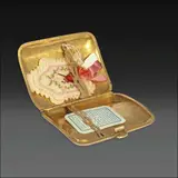 A 14k Cigarette Case, Untitled, A 14k yellow gold cigarette case of concave rectangular hinged design. Both sides are adorned with intricate floral and scrolling engravings, beautifully framing a central reserved space ideal for personalized initial engraving. From the 1920s through the 1950s, smoking accessories like this were highly fashionable and used by both men and women.<br/><br/>Inside the cigarette case is a beautifully embroidered scapular of the Sacred Heart of Jesus, featuring an inscription on the reverse: “Detente!... el Corazón de Jesús está conmigo,” which translates to “Stop!... the Heart of Jesus is with me.” <br/><br/>card, a collectible item famously distributed by major tobacco companies during the early to mid-1930s as a promotional gift with cigarette purchases. <br/><br/>The piece is signed BE, hallmarked 14k, numbered 30.<br/><br/>Accompanying this is a W.D. & H.O. playing