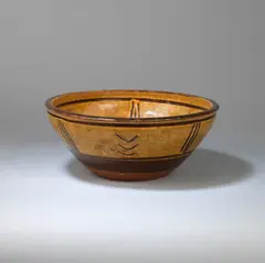 Bowl by Michael Cardew, circa 1932, Earthenware, dark amber glaze over a cream slip with finger wiped designs, offered Dec 2023