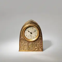 'Bookmark' pattern desk clock by Tiffany Studios, circa 1910, Polished gilt bronze, arched form cast with foliate panels, movement with Arabic numerals, sold Jun 2023