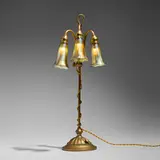 Adjustable three-light Lily lamp by Tiffany Studios, c. 1910, acid-etched and gilt bronze, hand-blown Favrile glass, sold Jul 2025