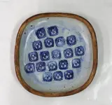 Len Castle, Unusual stoneware dish with unglazed textured ochre exterior, the interior with a repeating stamp design.