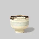 Lucie Rie, Footed bowl, circa 1979, Porcelain, matt white glaze over concentric inlaid blue lines repeated inside and out, dripping manganese lip