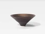 Dame Lucie Rie, A Conical Bowl, circa 1980, porcelain, covered in manganese with vertical incised lines to the interior and exterior