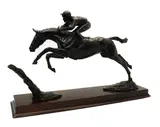 Priscilla Hann, Untitled, Priscilla Hann (b. 1943) a bronze figure of a jockey and racehorse jumping a fence, on a rectangular mahogany base