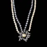 Untitled by A Faux Pearl Pendant Necklace, A ribbon pendant centered with a faux mabe pearl and accented with crystals hang from a double strand of gray and white , offered Jul 2026
