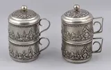 2 Theesets, 3-delig, Twee driedelige Djokja zilveren theesets met rondom floraal drijfwerk, 800/000, ø8cm., H,