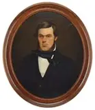 Unsigned, Portrait of a Belfast, Maine Merchant, Oval oil on canvas half portrait shows a young man with brown hair and brown beard wearing a black suit with white shirt