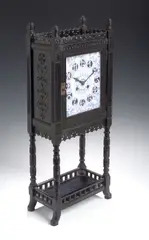 Lewis Foreman Day, An Aesthetic Movement ebonised wood clock,, rectangular enamel dial decorated in blue and white with flowers (cracked), the case with turned uprights and pieced galleries,