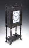 Lewis Foreman Day, An Aesthetic Movement ebonised wood clock,, rectangular enamel dial decorated in blue and white with flowers (cracked), the case with turned uprights and pieced galleries,