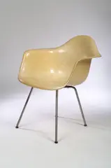 An early Shell Chair by Charles and Ray Eames, manufactured by Zenith Plastic/ Herman Miller, yellow fibre-glass shell, tubular metal legs,, offered Nov 2004