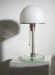 Wilhelm Wagenfeld, Tischlampe aus Glas“ - Modell: MT 9 (Vorarbeiten von Carl Jacob Jucker). 1923/24 / Ausführung 1924, Kristallglas, Glasrohr mit eingeschmolzenem blauen Faden; Messing, Stahl, vernickelt; Technikporzellan; originale Verkabelung – Hersteller: Metallwerkstatt des Staatlichen Bauhauses Weimar. 37,5 cm; Ø 17 cm (14 ¾ in.; Ø 6 ¾ in.)