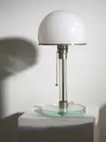Wilhelm Wagenfeld, Tischlampe aus Glas“ - Modell: MT 9 (Vorarbeiten von Carl Jacob Jucker). 1923/24 / Ausführung 1924, Kristallglas, Glasrohr mit eingeschmolzenem blauen Faden; Messing, Stahl, vernickelt; Technikporzellan; originale Verkabelung – Hersteller: Metallwerkstatt des Staatlichen Bauhauses Weimar. 37,5 cm; Ø 17 cm (14 ¾ in.; Ø 6 ¾ in.)