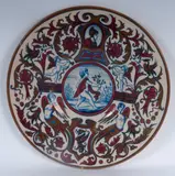 Paolo Rubboli, Polychrome ceramic pomp plate, Full-surface with a slight central recess. Decorated with swirls of cherubs and harpies and figures of young men