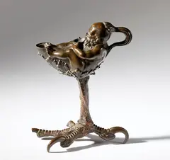 Andrea Riccio, Dwarf-shaped lamp on a bird of prey's leg, Bronze with reddish patina on black traces.