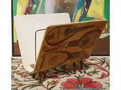 Screen-printed wooden magazine rack by Piero Fornasetti, decorated with musical instruments, offered Jul 2026
