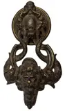 Giuseppe de Levis, Door knocker, The knocker depicts the head of a bearded man supported by a pair of dolphins who bite his ears. The tails of