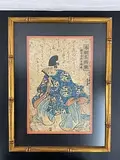 Yoshikazu, This artwork by Utagawa Yoshikazu is a framed Japanese woodblock print featuring a nobleman or samurai dressed in an elaborate blue robe with intricate designs. The figure is depicted in a traditional seated pose, Lithograph