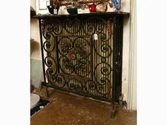 Green lacquered wrought iron panel with golden details by Gilbert Poillerat, 1902, mounted as a radiator cover with wooden top painted in imitation of green marble, offered Dec 2021