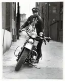 Charles Harris, (American/Pittsburgh, 1908-1998), Woman wearing dark cap with eagle, mounting motorcycle decorated with flags in an alley, taken c.1940-1946, later