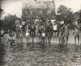 Teenie (American/Pittsburgh, 1908-1998), Group of Children Posed under Shower from Fire Hydrant, taken 1947, printed c.1980s, matte by Lawren Harris, photograph, offered Sep 2023