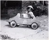 Charles Harris, Boy wearing helmet and seated in toy tank, Francis Street at Wylie Avenue, Hill District