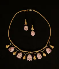 Giacinto Melillo, Collier und Paar Ohrringe (Demi-Parure) mit Theatermasken im Stil des Archeological Revival und nach Vorbild des sog. Ruvo-Colliers in Neapel, Um 1870, Gold, gegossen; Golddraht; Koralle, plastisch geschnitten; 14 Diamantrosen, Antwerpener Rosenschliff. 43,5 cm und 3,7 cm (17 ⅛ in. und 1 ½ in.)