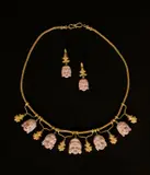 Giacinto Melillo, Collier und Paar Ohrringe (Demi-Parure) mit Theatermasken im Stil des Archeological Revival und nach Vorbild des sog. Ruvo-Colliers in Neapel, Um 1870, Gold, gegossen; Golddraht; Koralle, plastisch geschnitten; 14 Diamantrosen, Antwerpener Rosenschliff. 43,5 cm und 3,7 cm (17 ⅛ in. und 1 ½ in.)