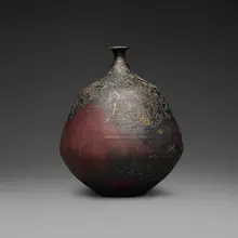 Bottle form with curved neck and lip by Gertrud and Otto Natzler, 1973, earthenware with Sang Reduction Fired glaze with flame marks, iridescence, and copper pools, sold Jun 2026