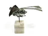Abstract metal sculpture depicting an animal in flight, mounted on a white by Charles Nagel, marble cube base. The sculpture features a complex, openwork design with patinat, sold Dec 2025