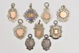 five with rose metal cartouches, two depicting buildings, one inscribed ' by Nine Silver Fob Medals, sculpture, sold Oct 2025