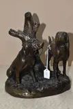 A PATINATED BRONZE SCULPTURE OF TWO BLOODHOUNDS tied to a tree, signed below the by Grace Mott Johnson, BRONZE, sold May 2025