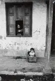 Enfant dans une caisse et femme à la fenêtre, Medellin, Colombie (Guatemala, Amérique du Sud). Circa 1955-60 by Jesse A. Fernández, Tirage argentique d’époque réalisé par le photographe, sous passe-partout et encadré, sold Nov 2025
