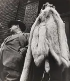 Man in Suit, Woman in Fur Coat, 1954 Silver gelatin print, printed later, image size 34.8 x 39cm, sheet size 50.2 x 40.5cm, with the photographer's stamp verso by Leon Levinstein, Silver gelatin print, printed later, image size, offered Nov 2025