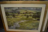 A mountainous river landscape with buildings and trees by Lance O'Gorman, oil on board, sold Jan 2025