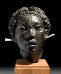 Tête d'africain by Jacques Darbaud, Épreuve en bronze à patine brune nuancée et deux boucles d'oreille en os sur socle carré e, sold Jun 2014