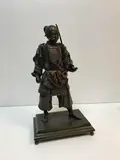 Statuette of a barefooted Samurai warrior holding a drawn sword by Miyao Eisuke Of Yokohama, bronze and gilt, sold Mar 2022