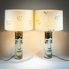 Zwei Tischleuchten 'Viso di Donna' mit Schirm 'Sole' by Piero Fornasetti, 1950, Metallblech, schwarz lackiert, schwarz-weißer Lithographiedekor, Messingblech, Metalldraht, Textilschirm, beige, schwarz, sold Oct 2026