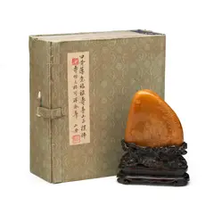 Inscribed poem on one side, translated as : "Blessed with longevity and serene happiness, one may enjoy an everlasting life.", signed "Shan Zhou". by Signature Of Liang Tongshu A Chinese Tianhuang Boulder Carving, It's with a finely carved fitted zitan stand and a fitted box., sold Oct 2026
