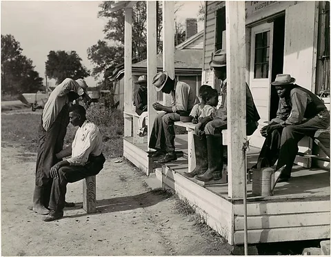 Marion Post Wolcott, [Haircutting in Front of General Store and Post Office on Marcella Plantation, Mileston, Mississippi]