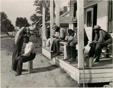 Marion Post Wolcott, [Haircutting in Front of General Store and Post Office on Marcella Plantation, Mileston, Mississippi]